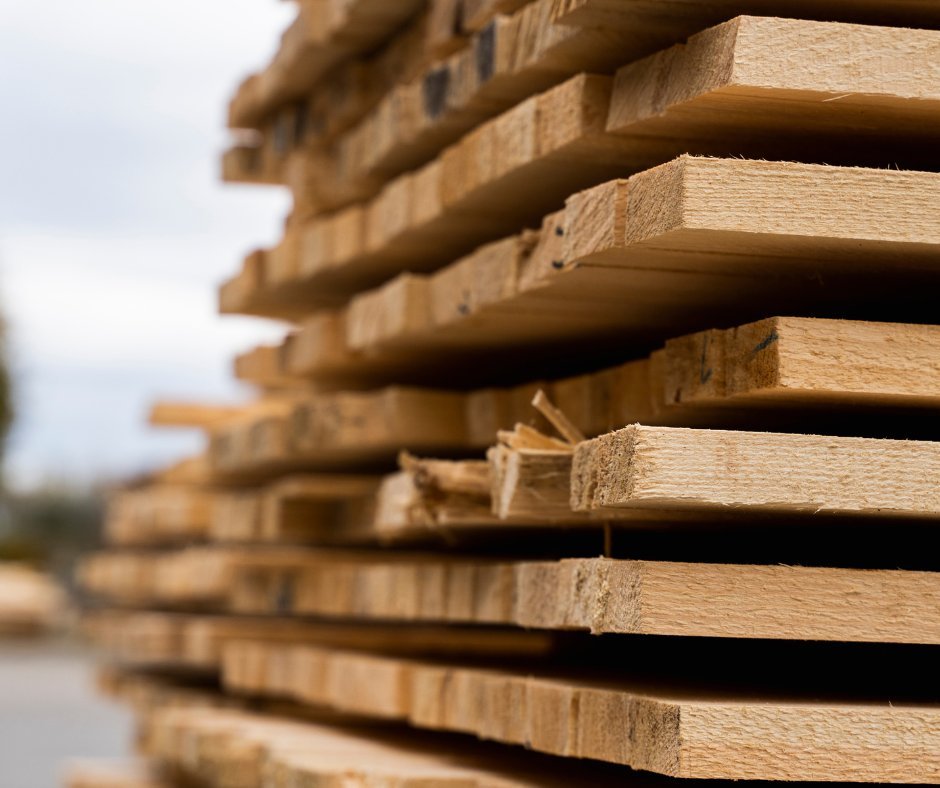 Pile de planches de bois fraîchement sciées en cour à bois — sortie de ligne de tronçonnage typique des scieries québécoises servies par CFI Industrie au Saguenay–Lac-Saint-Jean, en Mauricie et sur la Côte-Nord.