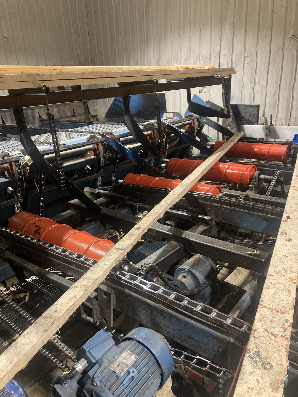 Sawmill chain conveyor with new custom orange centering rollers manufactured by CFI Industries for Opitciwan sawmill in Mauricie, Quebec