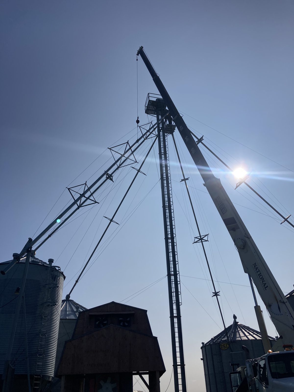 Twin galvanized commercial silo installation with central RAD elevator and transfer piping — industrial site in Saguenay–Lac-Saint-Jean, Quebec